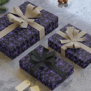 May include: Three wrapped gifts with a black and purple skull pattern. The gifts are tied with beige and black ribbons and bows. The gifts are on a grey surface.