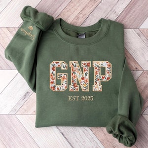May include: A green sweatshirt with a floral patterned "GNP" graphic and the text "EST. 2025" in gold.