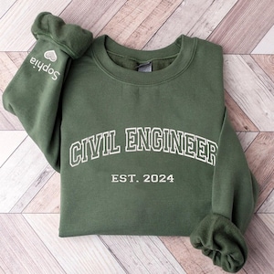 May include: A dark green sweatshirt with the text "CIVIL ENGINEER EST. 2024" in white on the front. The sweatshirt has a crew neck and long sleeves.