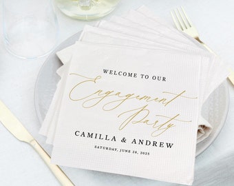 May include: White napkins with gold lettering that says "Welcome to our Engagement Party Camilla & Andrew Saturday, June 28, 2025".
