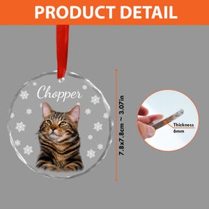 May include: A round, clear glass ornament with a cat image and the name "Chopper" printed on it. The ornament is 7.8 x 7.8 cm (3.07 in) and 6 mm thick. It features a red ribbon for hanging.
