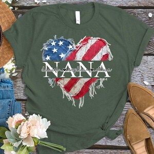 K&ouml;nnte beinhalten: Gr&uuml;nes T-Shirt mit einem herzf&ouml;rmigen Design, das die amerikanische Flagge und das Wort "NANA" zeigt. Unter dem Wort "NANA" stehen die Namen "Daniel, Sophia, Ethan". Das T-Shirt hat einen l&auml;ssigen Stil.