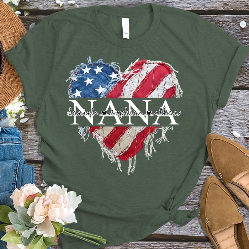 K&ouml;nnte beinhalten: Gr&uuml;nes T-Shirt mit einem herzf&ouml;rmigen Design, das die amerikanische Flagge und das Wort "NANA" zeigt. Unter dem Wort "NANA" stehen die Namen "Daniel, Sophia, Ethan". Das T-Shirt hat einen l&auml;ssigen Stil.
