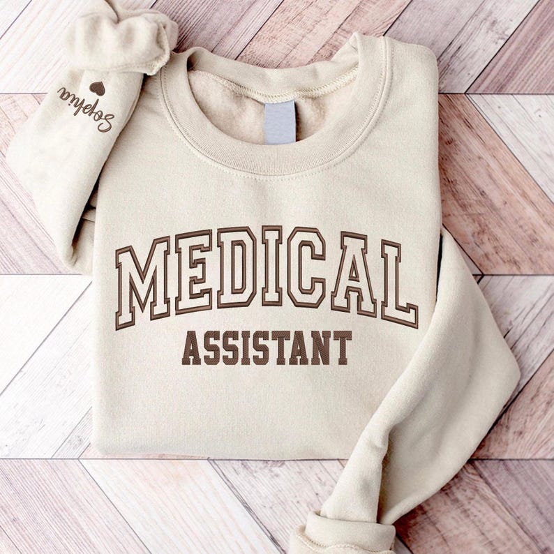 May include: A beige sweatshirt with the text "MEDICAL ASSISTANT" in brown lettering.