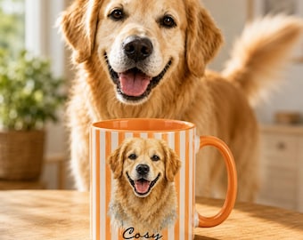 Op de afbeelding: Een keramische mok met een verticaal oranje en wit gestreept patroon. De voorzijde van de mok toont een gedetailleerde illustratie van een golden retriever met een open bek, met het woord Cosy in zwarte cursieve letters eronder.