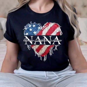 K&ouml;nnte beinhalten: Schwarzes T-Shirt mit einem herzf&ouml;rmigen Design in den Farben der amerikanischen Flagge. Das Herz ist in Abschnitte mit Sternen und Streifen unterteilt. Das Wort "NANA" ist in der Mitte aufgedruckt, darunter die Namen "danielle sophia ethan".