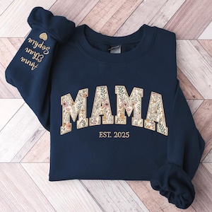 May include: Navy blue sweatshirt with a floral print "MAMA" design and the text "EST. 2025" in gold.
