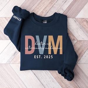 May include: Navy blue sweatshirt with the text "DVM doctor of veterinary medicine EST. 2025" in colorful letters.