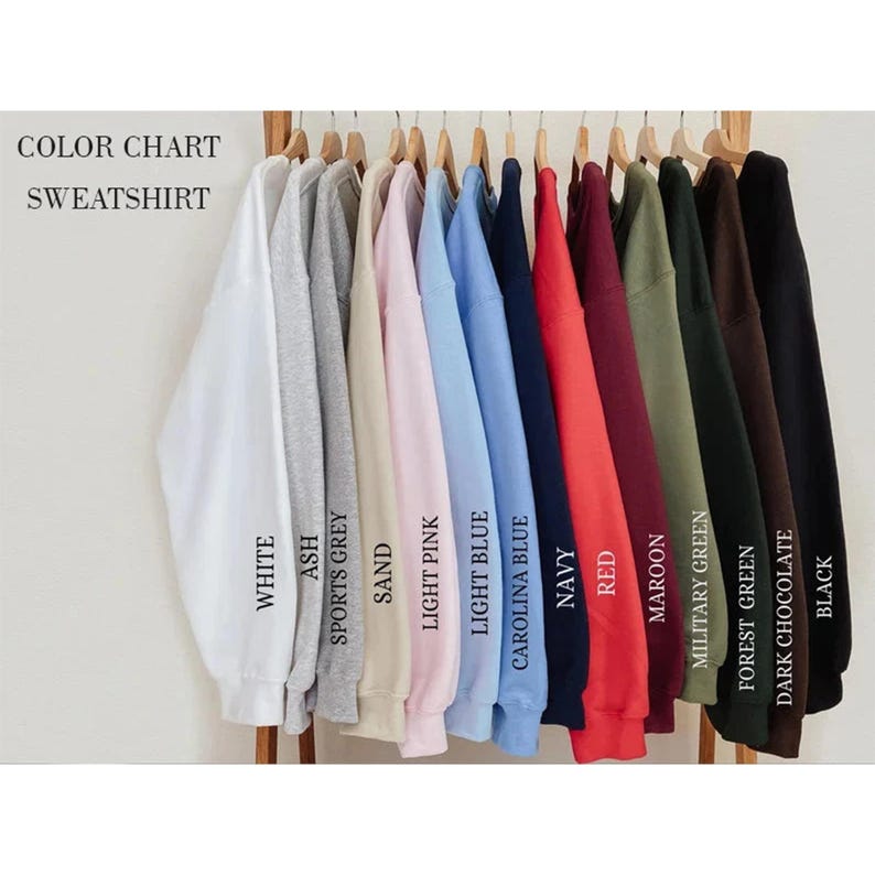 May include: A sweatshirt colour chart showing a range of hues. The colours include white, ash, sports grey, sand, light pink, light blue, carolina blue, navy, red, maroon, military green, forest green, dark chocolate, and black.