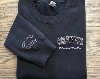 May include: Black sweatshirt with white text that says "Sharpei mama" and a stylized image of a Sharpei dog on the sleeve.