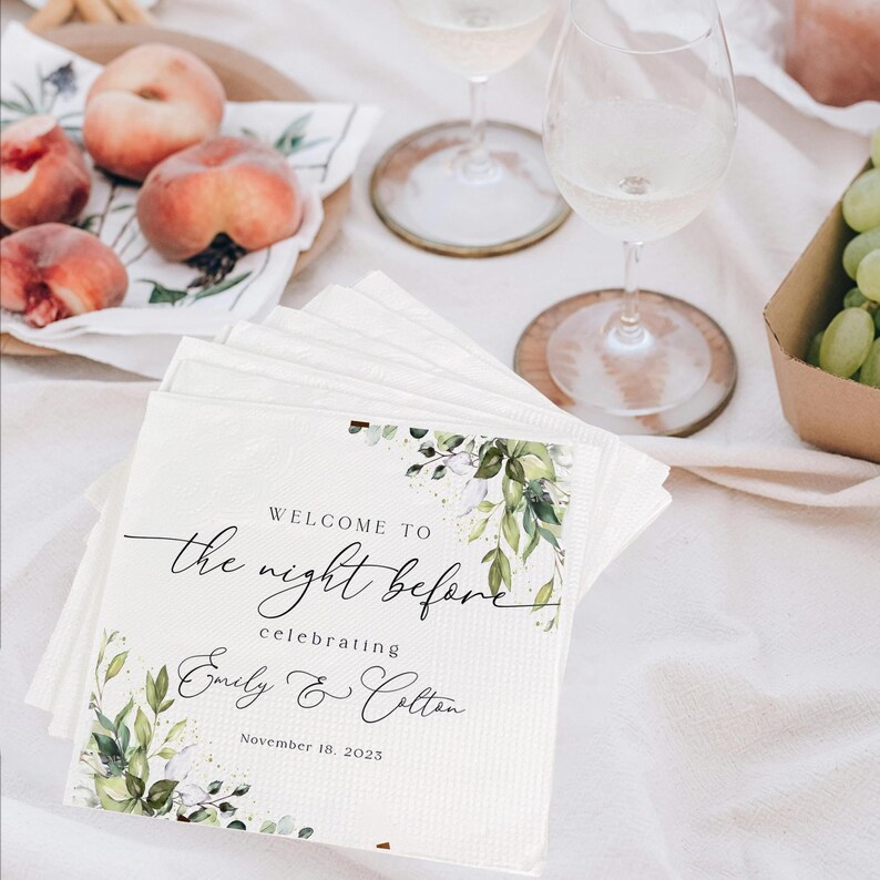 May include: White napkins with a green and white floral design. The napkins have the text "Welcome to the night before celebrating Emily & Colton November 18, 2023" printed on them.