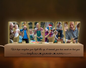 May include: A wooden light-up sign spelling "PAWPAW" with photos of a family inside each letter. The base of the sign has the text "We hope everytime you light this up, it reminds you how much we love you" and the names "sophia james nova" written below.