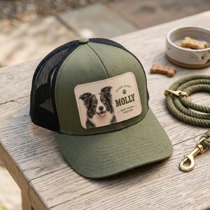 May include: An olive green trucker hat with a black mesh back and a rectangular leather patch on the front. The patch features a portrait of a black and white dog, a paw print icon, and the text: GOOD DOGS, MOLLY, BEST FRIEND FOREVER.