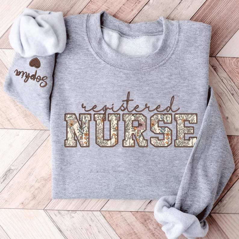 May include: A gray sweatshirt with the text "registered NURSE" in brown letters with a floral pattern. The letters are outlined in brown.