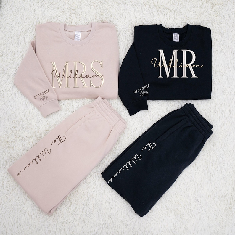 May include: Matching beige and black sweatshirt and sweatpants sets. The beige set includes a sweatshirt with "MRS William" in gold script and sweatpants with "The Williams" in script. The black set has "MR William" and "The Williams" in white script.