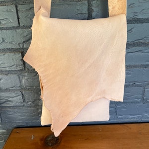 May include: A light brown leather crossbody bag with a flap closure. The bag is made of a soft, supple leather and has a simple, classic design.