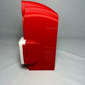 May include: A red and white electrical outlet cover with a hinged door. The cover has a rectangular shape and a textured surface.