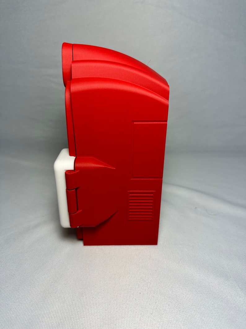 May include: A red and white electrical outlet cover with a hinged door. The cover has a rectangular shape and a textured surface.