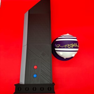 May include: A black and gray obelisk-shaped object with red and blue buttons, and a spherical object with white and purple stripes and gold text, set against a red background.