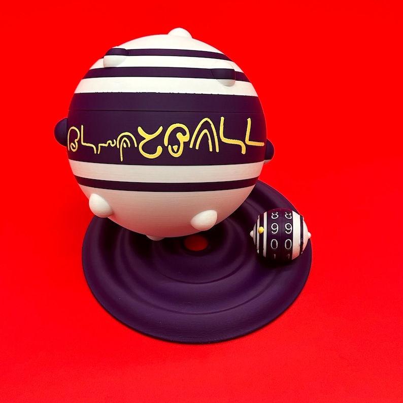 May include: A spherical, white and purple object with horizontal stripes and gold lettering, resting on a purple base. A smaller, striped, cylindrical object with numbers sits nearby. The background is a solid red.