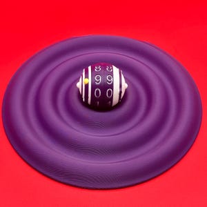 May include: A close-up shot of a white and black striped object with numbers on it, resting on a purple, rippled surface. The object has a yellow dot on its side. The background is a solid red.