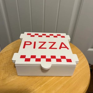 Op de afbeelding: Witte kartonnen pizzadoos met rode geruite rand en het woord "PIZZA" in rode letters.