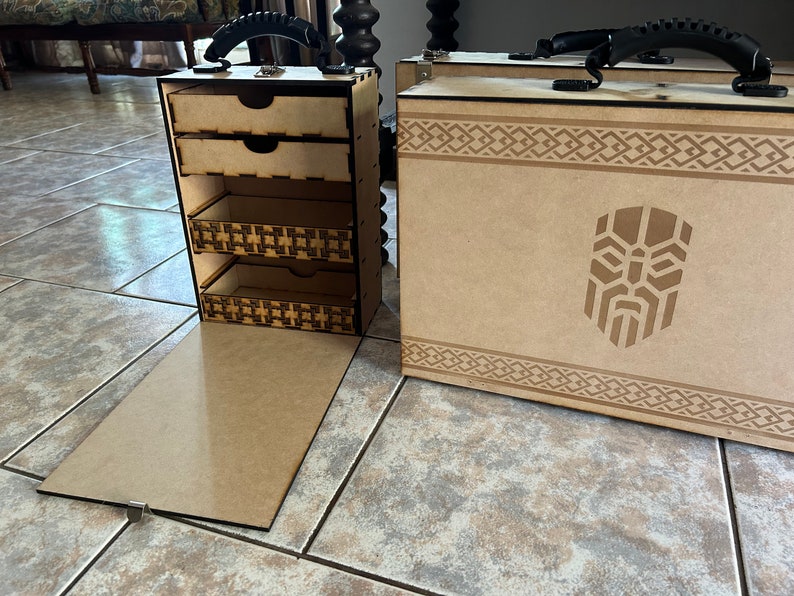 Op de afbeelding: Twee houten opbergdozen met een decoratief ontwerp. Een doos heeft een scharnierend deksel en drie laden. De andere doos heeft een scharnierend deksel en een afbeelding van een gezicht met een baard.