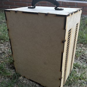 May include: A wooden box with a black plastic handle. The box has a wood grain finish and is made of plywood. The box has a series of slots on one side.