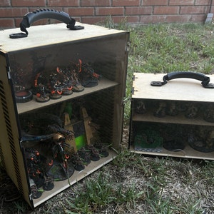 May include: Two wooden display cases with clear acrylic lids and black handles. The cases are filled with miniature figures and models, including a large, detailed robot.