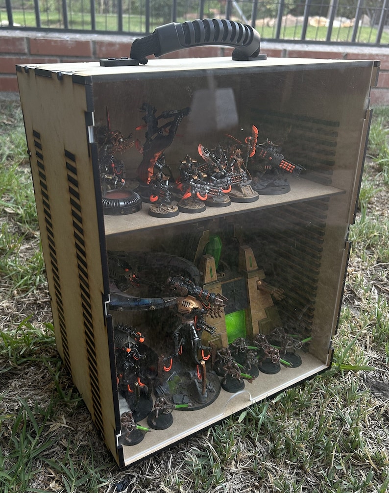 May include: A wooden display case with a clear acrylic lid and shelves. The case is filled with miniature painted figures of robots and vehicles. The figures are painted in shades of black, orange, and green.