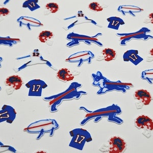 May include: A collection of small, die-cut shapes featuring a football team theme. The shapes include blue and red helmets, blue jerseys with the number 17, football players, and blue dog silhouettes with a red stripe.