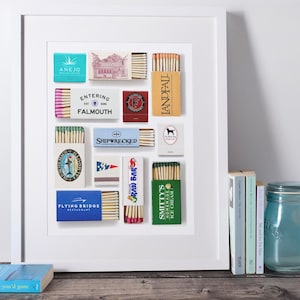 Könnte beinhalten: Ein gerahmter Druck mit einer Sammlung von Streichholzschachteln im Vintage-Stil mit verschiedenen Logos und Texten, darunter Anejo, Entering Falmouth, Landfall, Shipwrecked, Old Silver Beach, Raw Bar, Flying Bridge Restaurant und Smitty's Homemade Ice Cream.