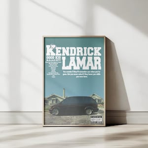 Puede incluir: Póster enmarcado con la portada del álbum "Good Kid, M.A.A.D City" de Kendrick Lamar. Fondo turquesa con texto blanco, título y letras. Un coche negro frente a casas. Pegatina de "Parental Advisory" visible.