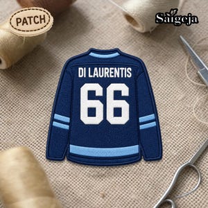 May include: A navy blue hockey jersey patch with the name "DI LAURENTIS" and the number "66" in white. The patch has light blue stripes on the sleeves and bottom. The word "PATCH" is on a wooden patch in the upper left corner.
