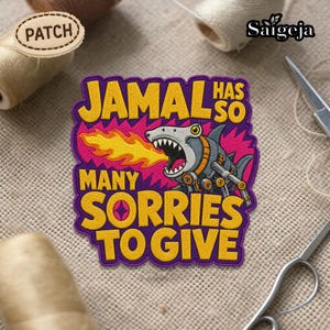 May include: Embroidered patch with the text "JAMAL HAS SO MANY SORRIES TO GIVE" in yellow, outlined in purple. The patch features a robotic shark breathing fire, set against a pink and purple background. The word "PATCH" is on a wooden tag.