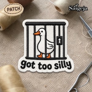May include: Embroidered patch featuring a white duck inside a black and white cage. The duck has an orange beak and feet. The text "Got too silly" is below the cage in black script. The patch is surrounded by white thread.