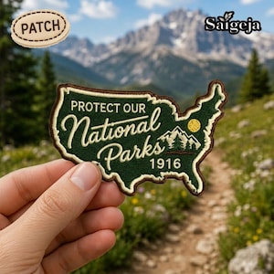 May include: An embroidered patch in the shape of the United States, featuring the text "PROTECT OUR National Parks 1916". The patch is green with brown edging and includes a mountain and sun graphic. A separate patch with the word "PATCH" is also visible.