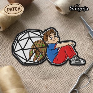 Puede incluir: Parche bordado con un niño de dibujos animados con camisa azul y pantalón rojo, apoyado en una forma geométrica con una figura marrón con forma de árbol. El parche tiene un borde negro y la palabra "PATCH" en una etiqueta separada.