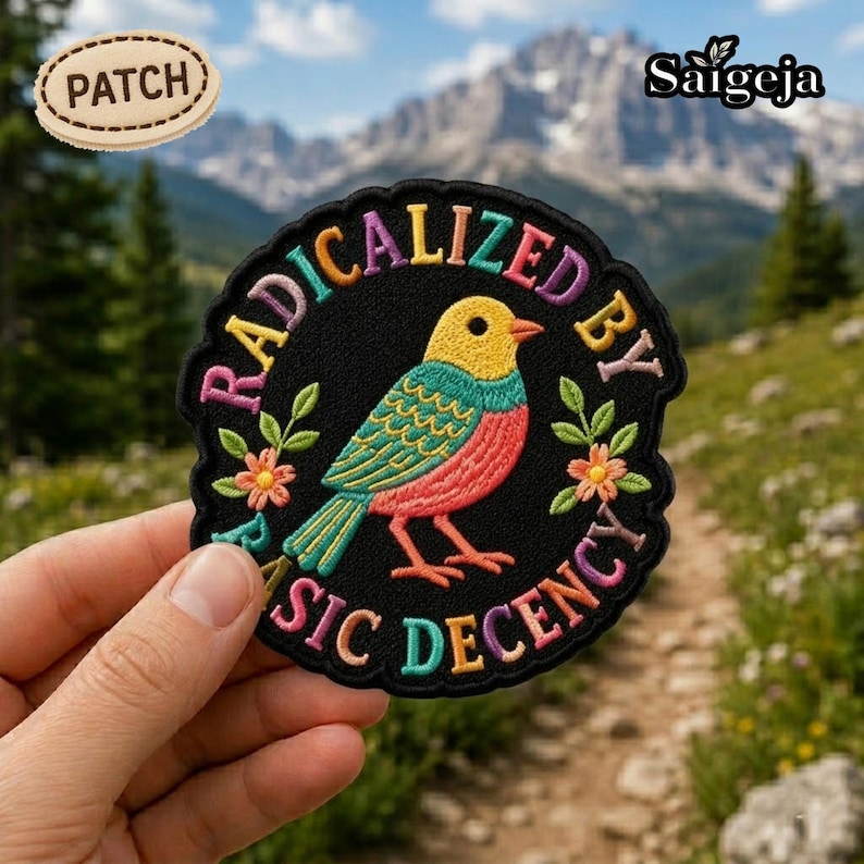 Pu&ograve; includere: Toppa ricamata con un design di uccello colorato e la scritta "RADICALIZED BY BASIC DECENCY" disposta a cerchio. L'uccello presenta tonalit&agrave; gialle, turchesi e rosse. &Egrave; visibile anche una toppa pi&ugrave; piccola con la parola "PATCH".