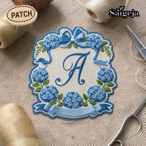 May include: Embroidered patch featuring the letter "A" in elegant script, surrounded by blue hydrangea flowers and ribbons. The patch has a light beige background and a light blue border. The word "PATCH" is on a small wooden tag.