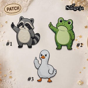 May include: Embroidered patches featuring a raccoon, a frog, and a duck, each giving the middle finger. The raccoon is gray and white, the frog is green, and the duck is white with an orange beak and feet. The patches are numbered #1, #2, and #3.