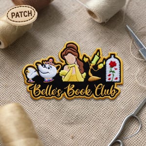 May include: Embroidered patch featuring Belle from Beauty and the Beast, with the text "Belle's Book Club." The patch includes images of Mrs. Potts, Lumiere, and the enchanted rose. The patch is black with gold and yellow accents.