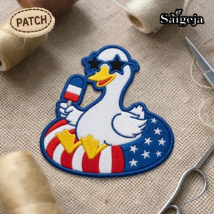 May include: Embroidered patch featuring a white duck wearing star-shaped sunglasses and a red, white, and blue floatie. The duck holds a popsicle with red, white, and blue stripes. The patch has the word "PATCH" on it.