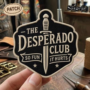 May include: Black and cream-colored embroidered patch with the text "THE DESPERADO CLUB" and a dagger design. The patch also includes the phrases "SO FUN" and "IT HURTS" with star accents. A smaller patch with the word "PATCH" is also visible.
