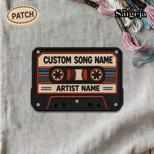 May include: Embroidered patch in the shape of a retro cassette tape. The patch is black with brown, blue, and orange details. It features the text "CUSTOM SONG NAME" and "ARTIST NAME". A smaller patch with the word "PATCH" is also visible.