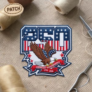 Può includere: Toppa ricamata con un design patriottico. Presenta il numero "250" in blu e bianco, con strisce rosse e bianche. Un'aquila marrone con le ali spiegate è centrata sotto, con uno stendardo che recita "American Independence 1776-2026".