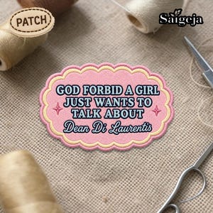 May include: A pink embroidered patch with the text "GOD FORBID A GIRL JUST WANTS TO TALK ABOUT Dean Di Laurentis". The patch has a scalloped edge with a light yellow border and star accents.