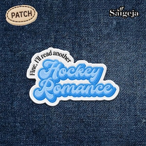 May include: A blue and white embroidered patch with the words "Hockey Romance" in a script font. The patch also includes the phrase "Fine, I'll read another". A smaller patch with the word "PATCH" is in the upper left corner.