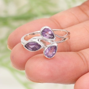 May include: A silver ring with three amethyst stones set in a leaf design.