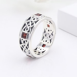 Peut inclure: Bague en argent avec un motif de nœud celtique et des pierres précieuses rouges. La bague est marquée "925" à l'intérieur.